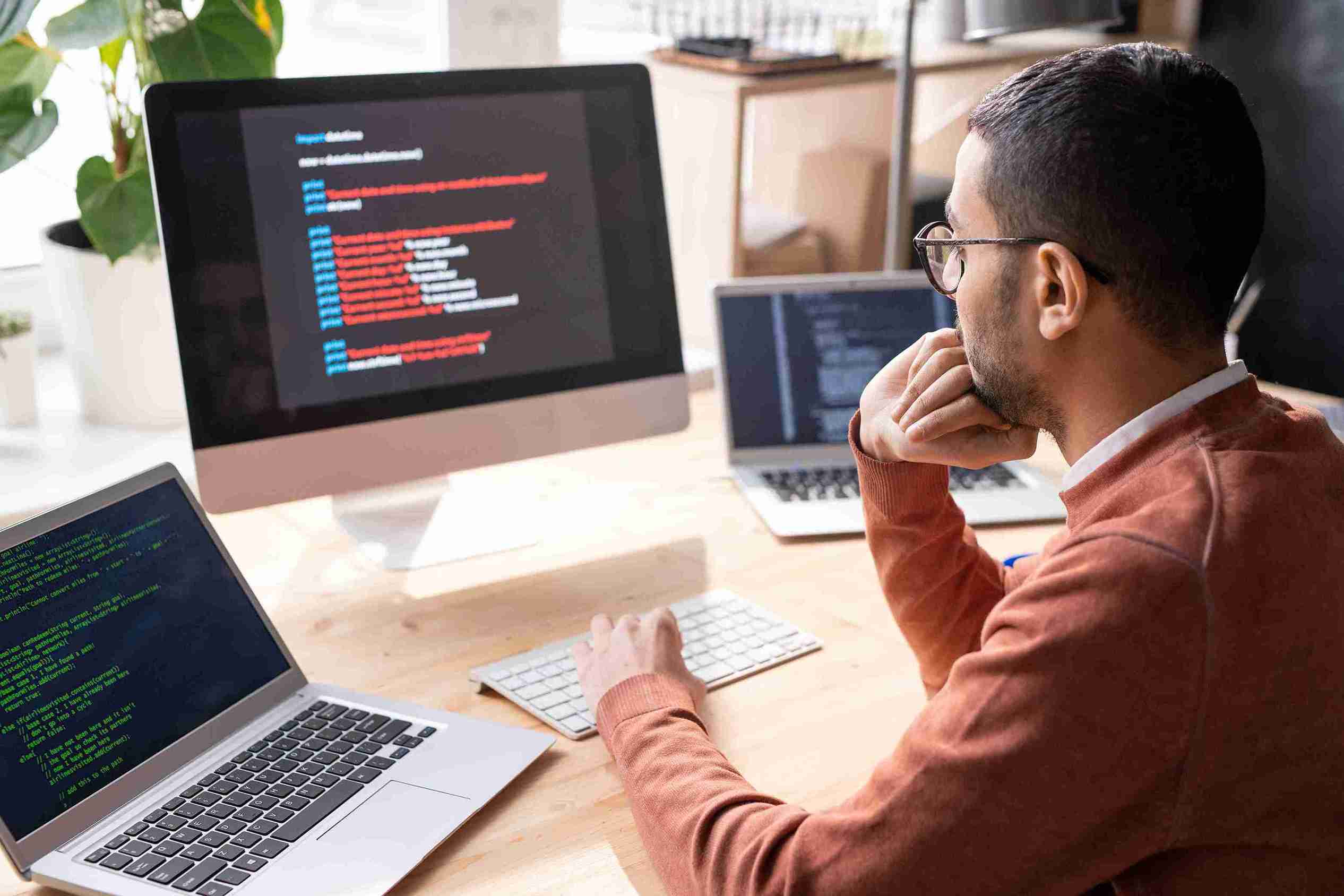 man-works-with-multiple-computer-screens-in-office