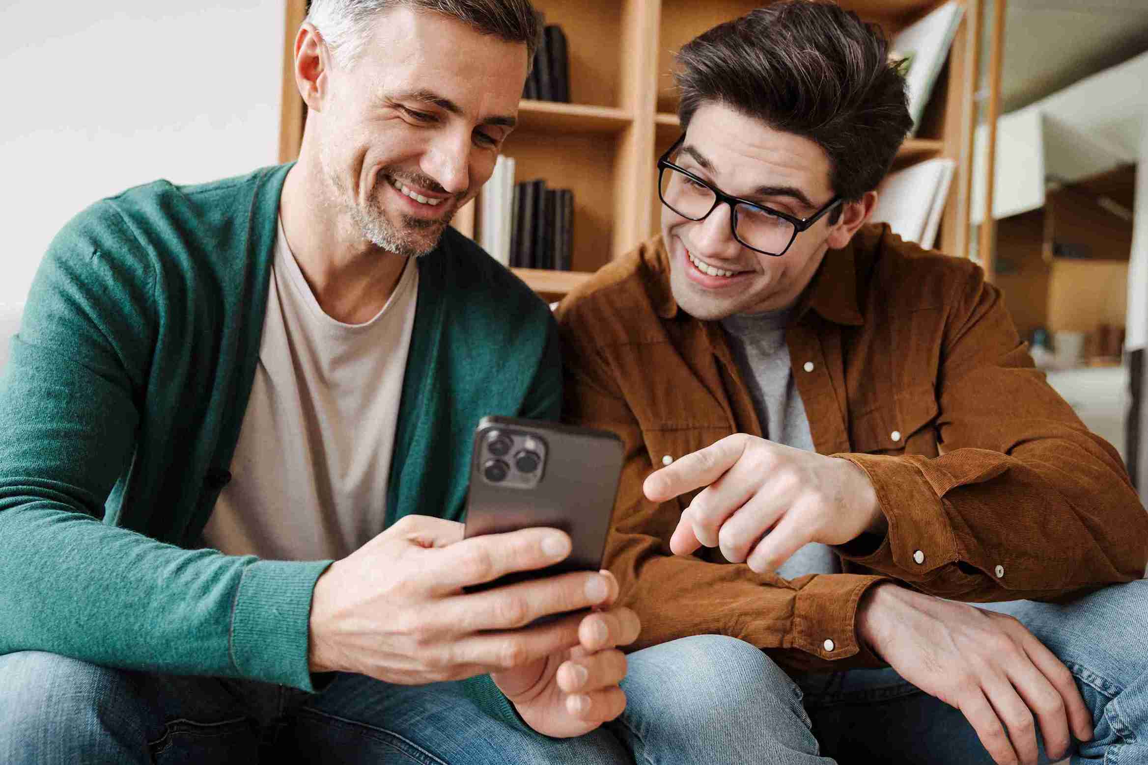 two-men-happily-looking-at-a-smartphone-indoors
