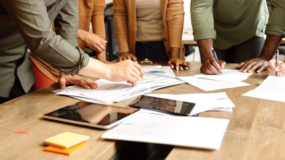 (In the image a group of people can be seen devising a social media strategy template)