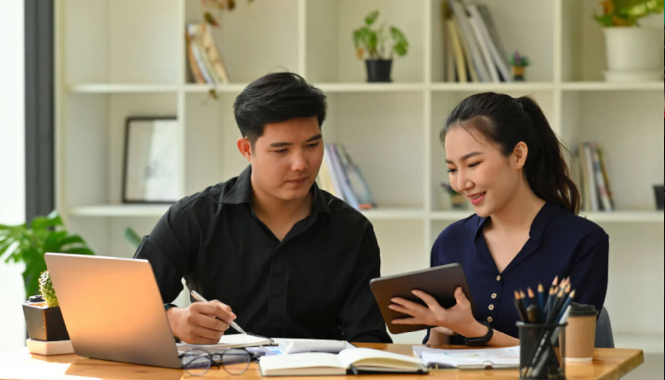 Two people reviewing information on a tablet and laptop, symbolizing smart assistant guidance and decision-making.