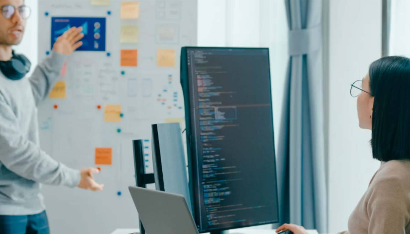 Developer leading a meeting, showcasing code on a large monitor during a discussion about AI localization.