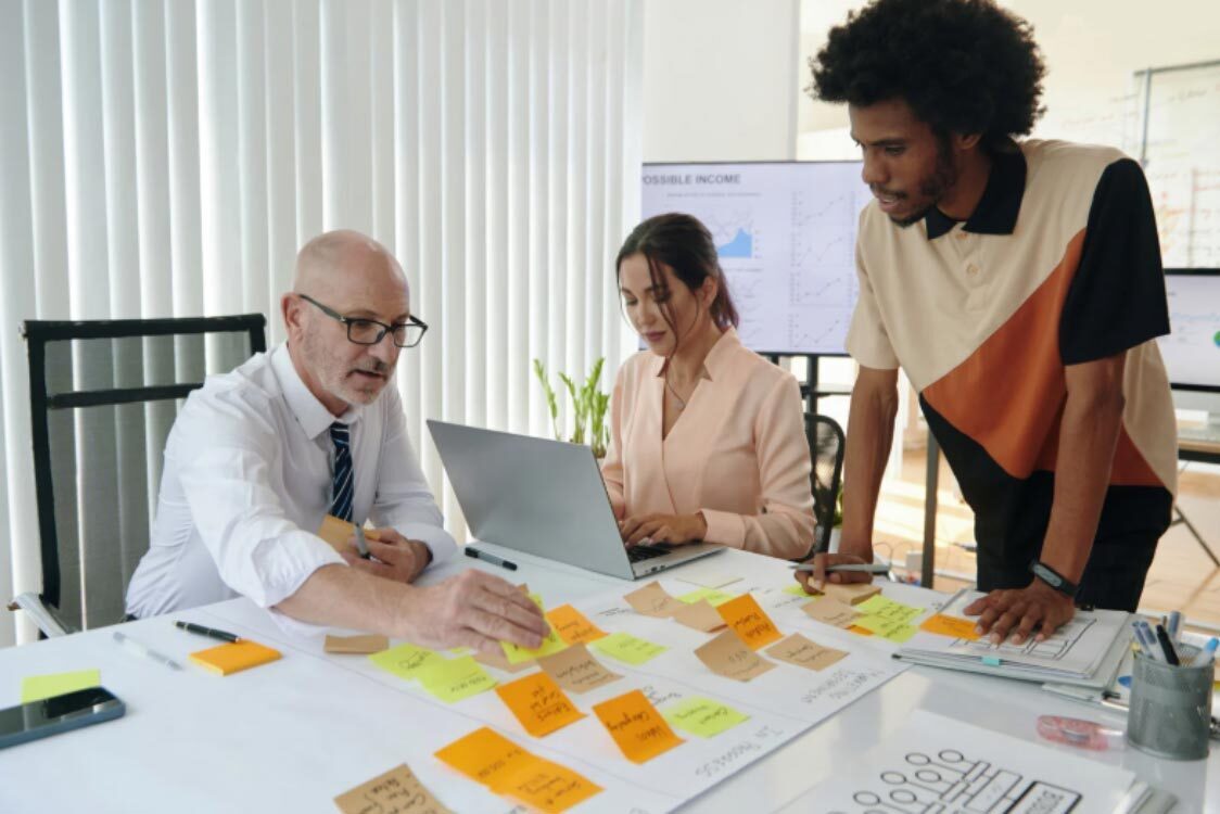 (A marketing team collaborating on a table filled with sticky notes to plan neuromarketing tactics for a new campaign.)