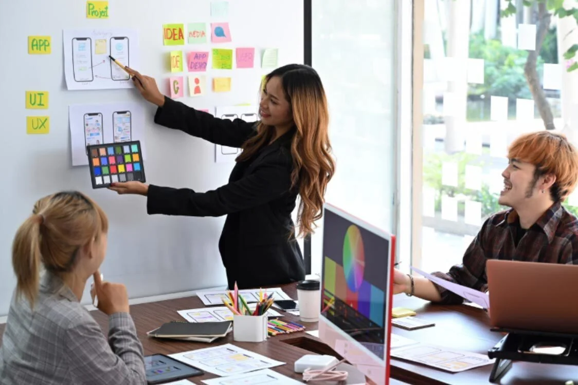 The Beginner’s Guide to User Interface Optimisation (A design team discussing user interface best practices and mobile app layouts on a whiteboard.)